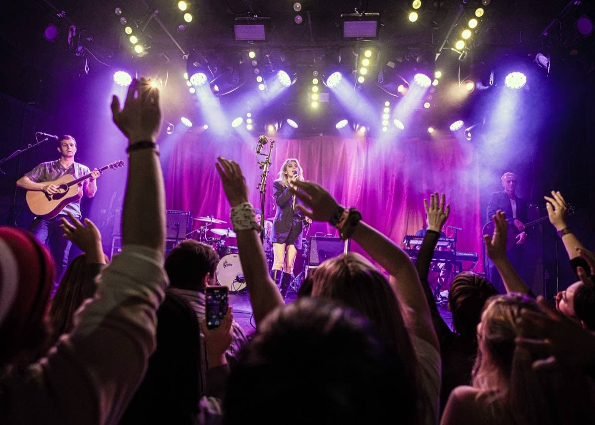 A band on a lit stage seen over a crowd