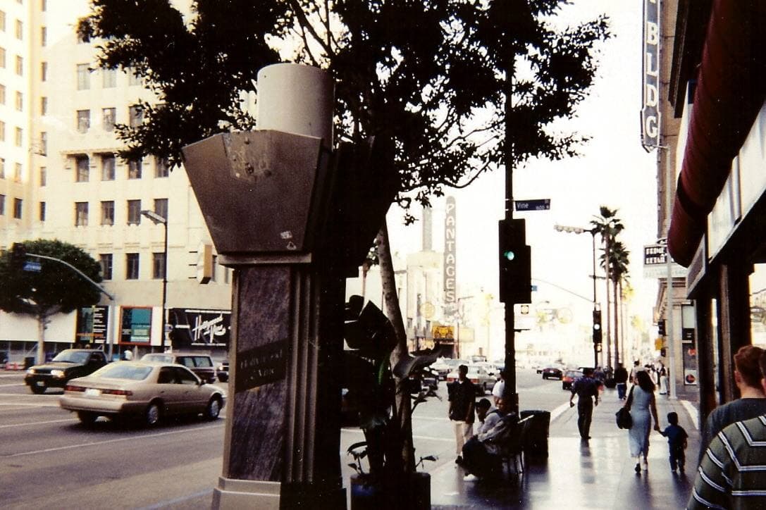 A busy intersection with palm trees and old office blocks