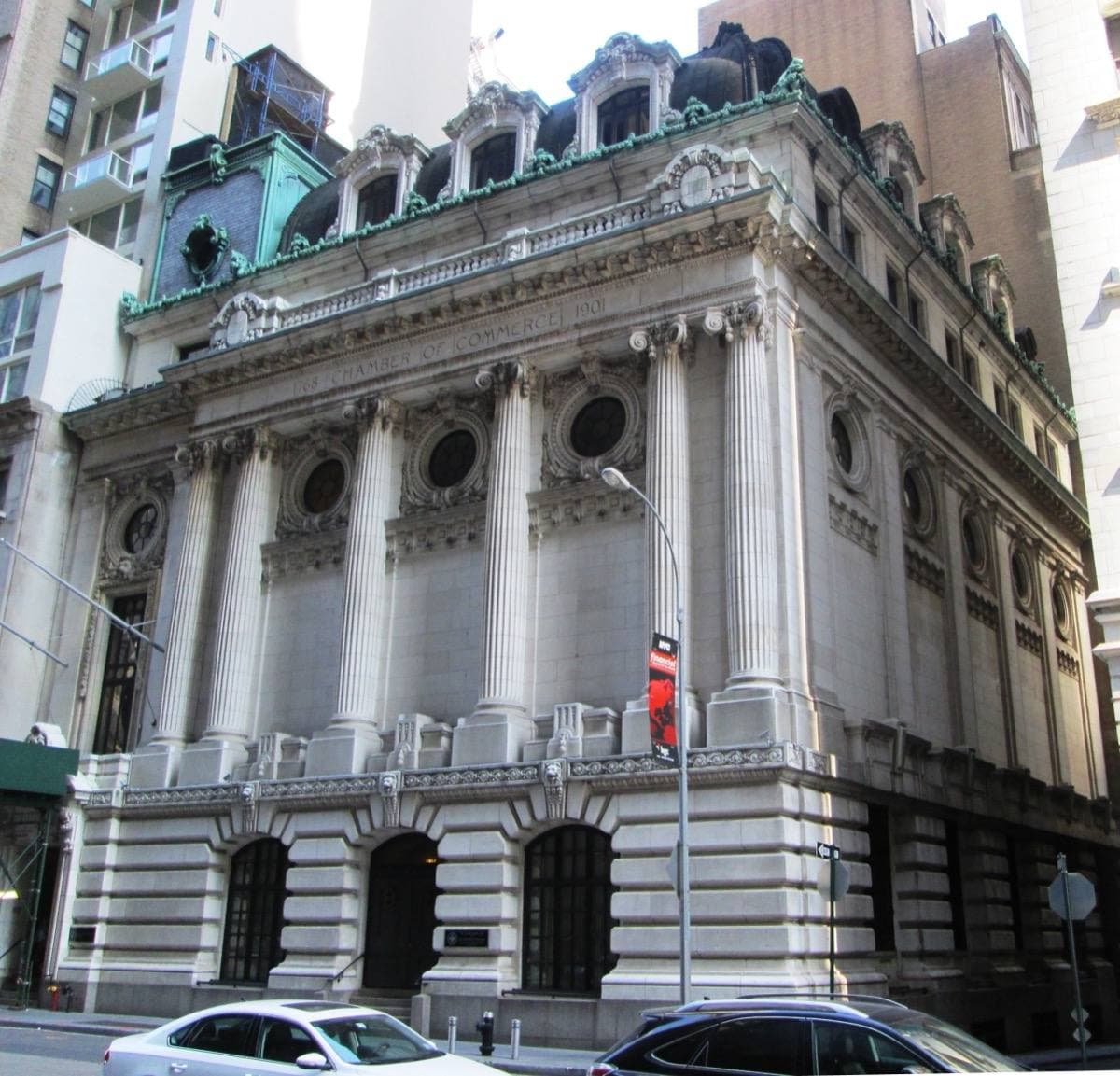 A white marble Beaux-Arts building with a copper mansard roof
