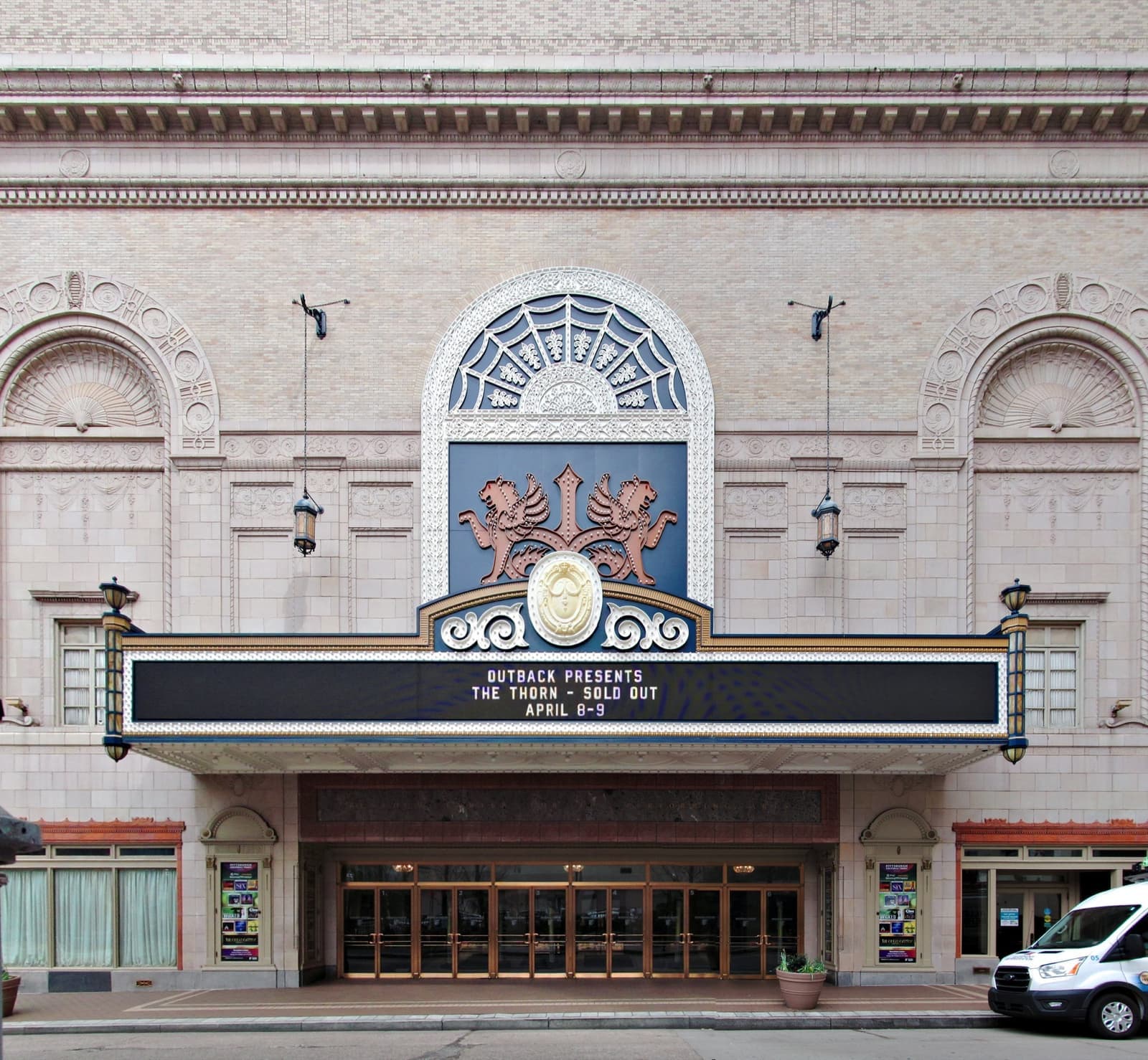 A theatre marquee over a stone entrance on a downtown street
