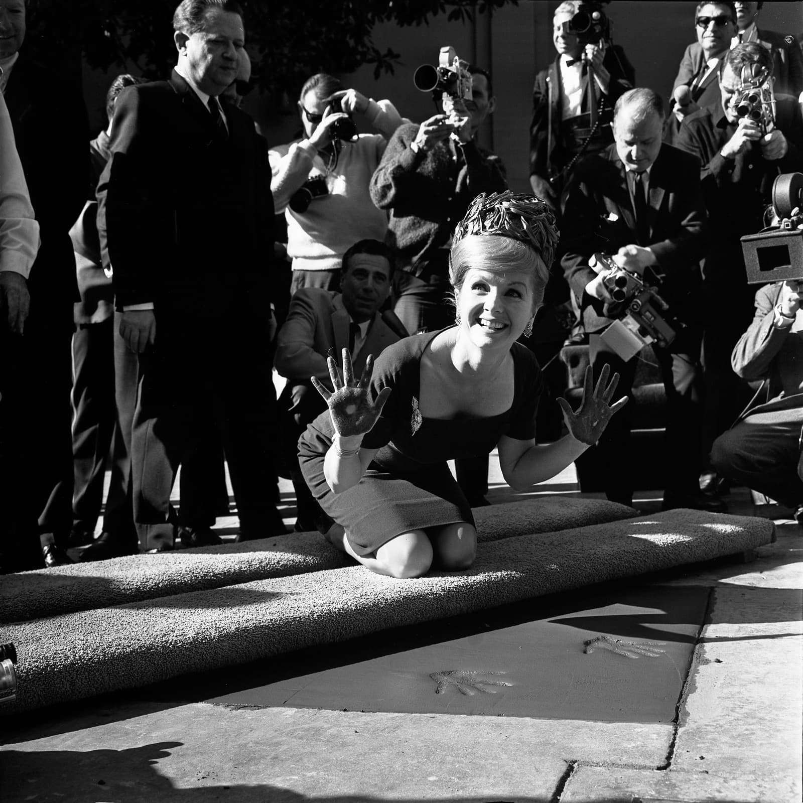 Debbie Reynolds smiling and holding up cement-covered hands