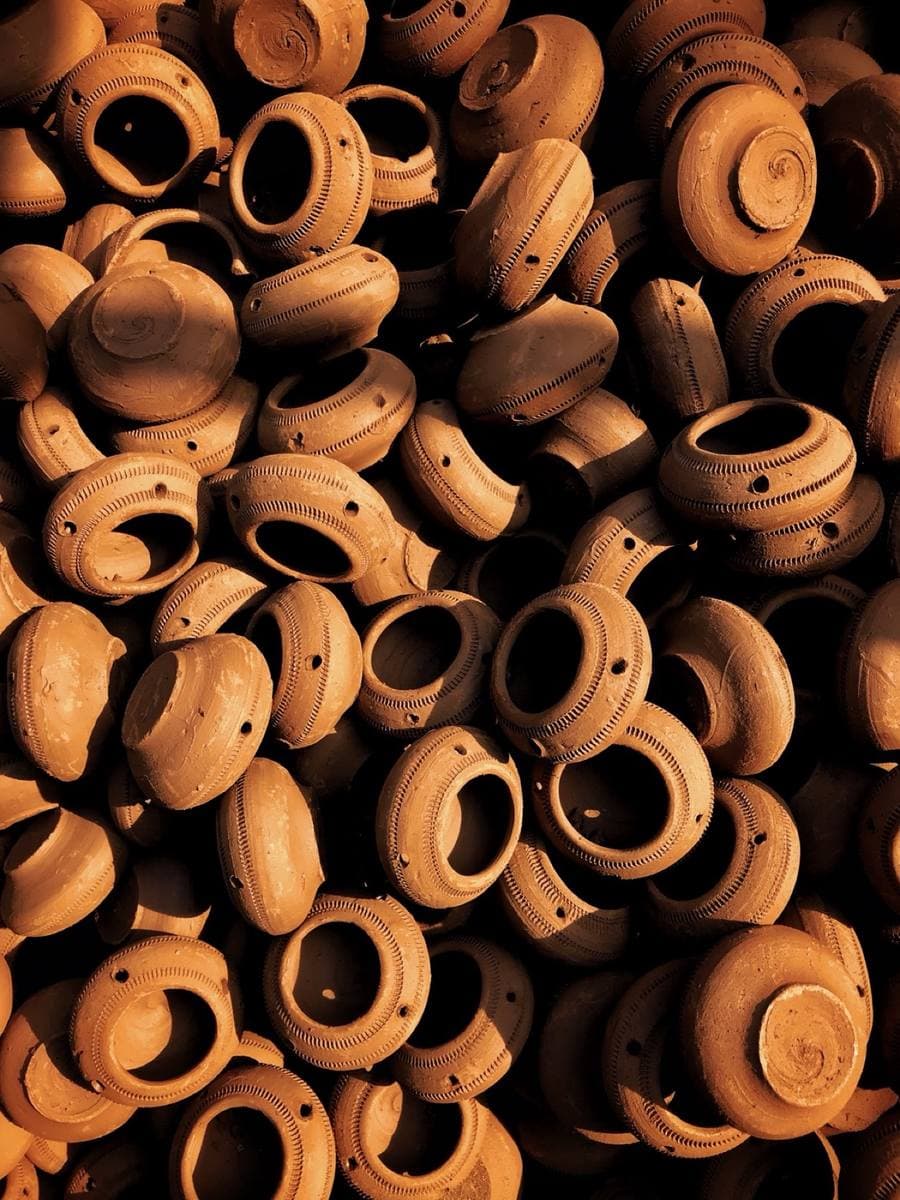 Colour photograph of a heap of small terracotta lamps with cut-out patterns