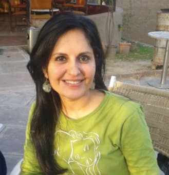 Colour photograph of Loveleen Tandan in a green top, smiling, outdoors