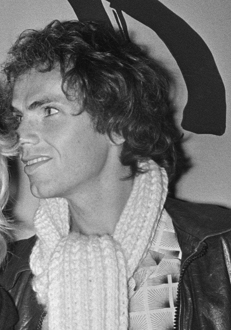 A young Jan de Bont with curly hair and a scarf, in profile