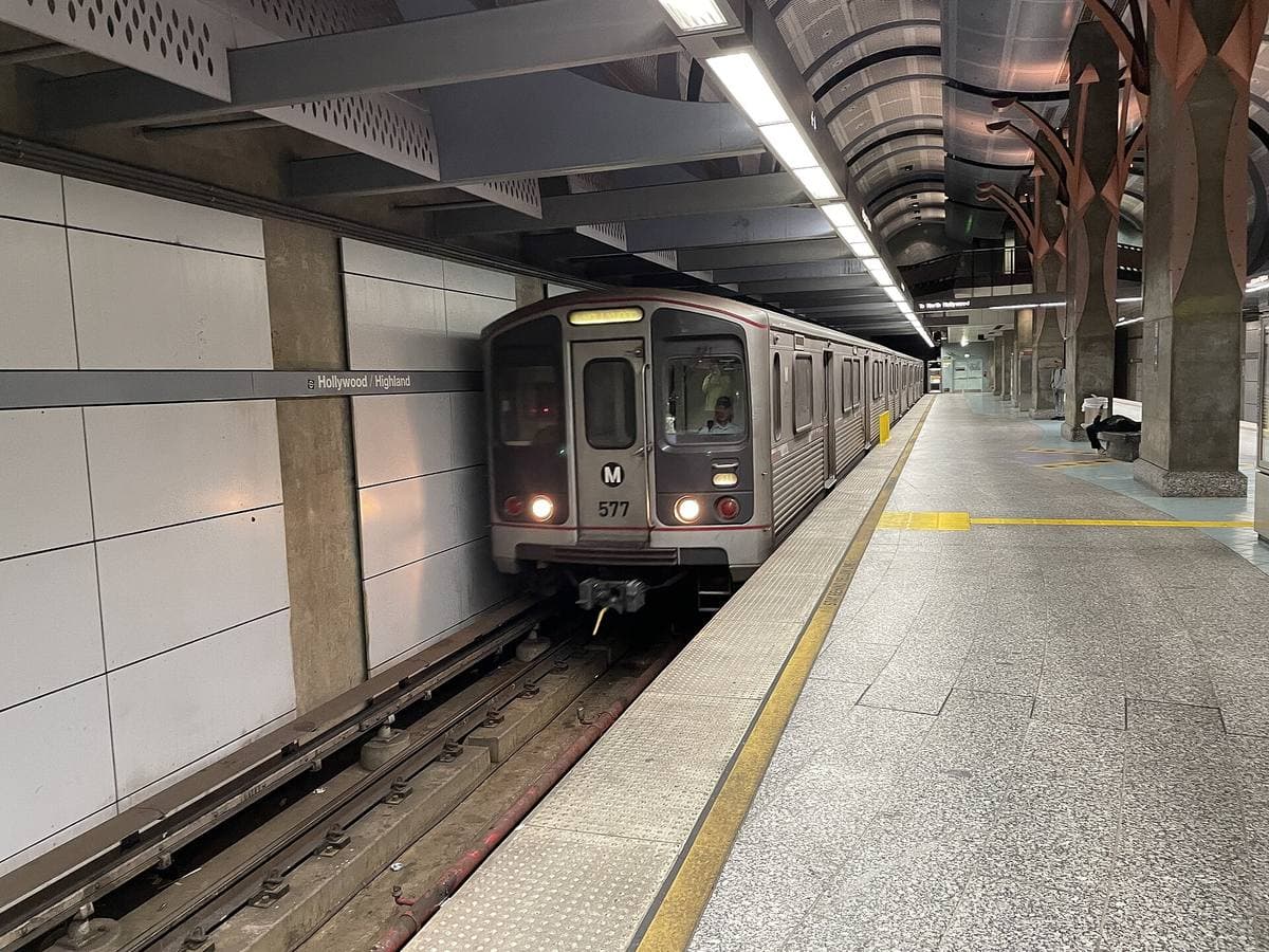A silver subway train arriving at an underground platform