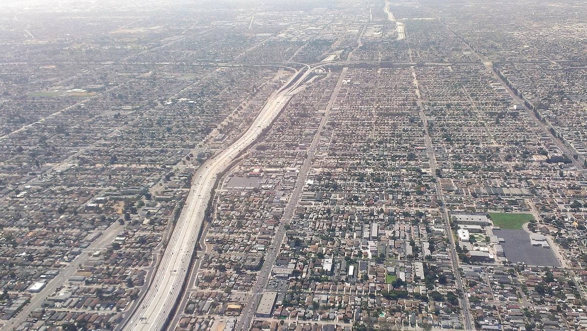 An aerial view of a freeway interchange with curving ramps over a grid of streets