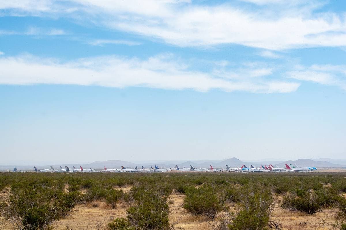 Rows of white airliners parked on desert scrubland under a big sky