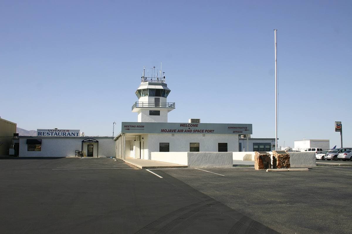 A low white airport building with a small control tower on an empty apron