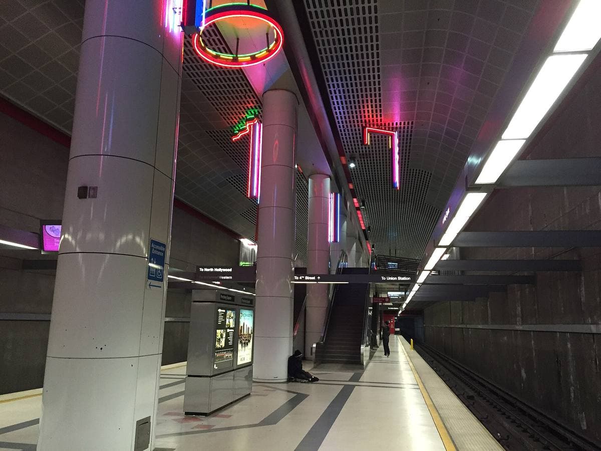 A long underground metro platform with pale columns and a train track