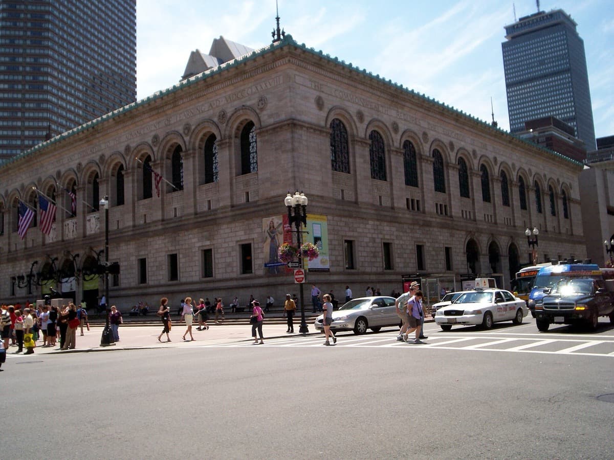 A grand stone library front with tall arched windows and a flight of steps
