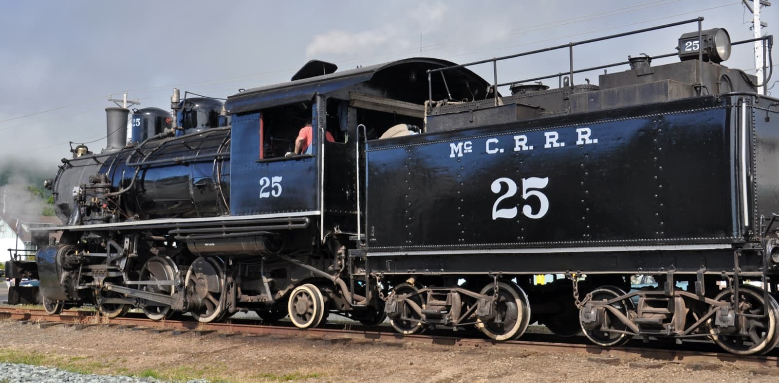 A black 1925 steam locomotive and tender lettered McC.R.R.R. 25, standing on track