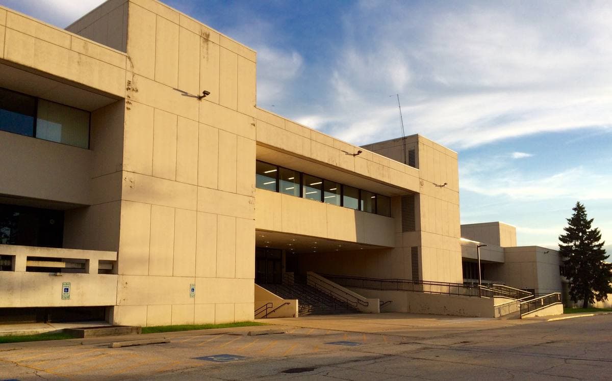The pale concrete front of the former Maine North High School in low evening sun