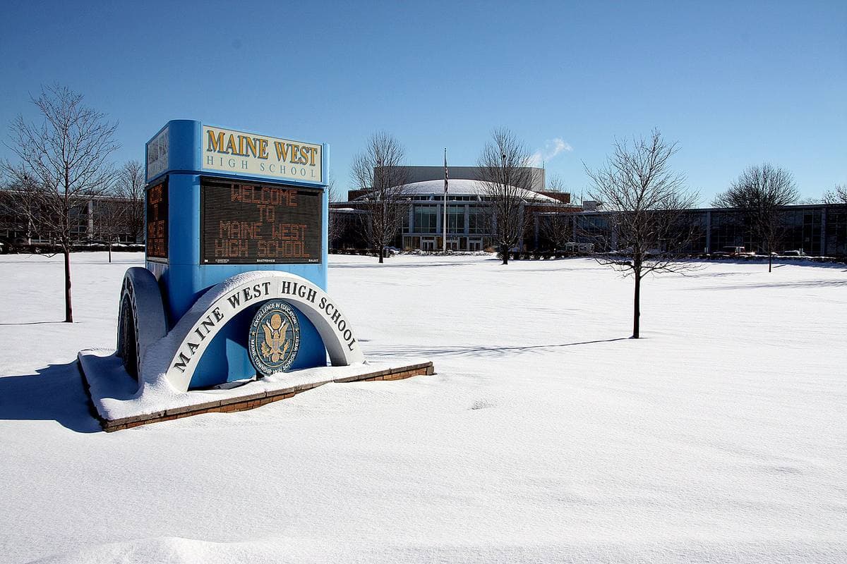 A school building across a snowy lawn under grey sky