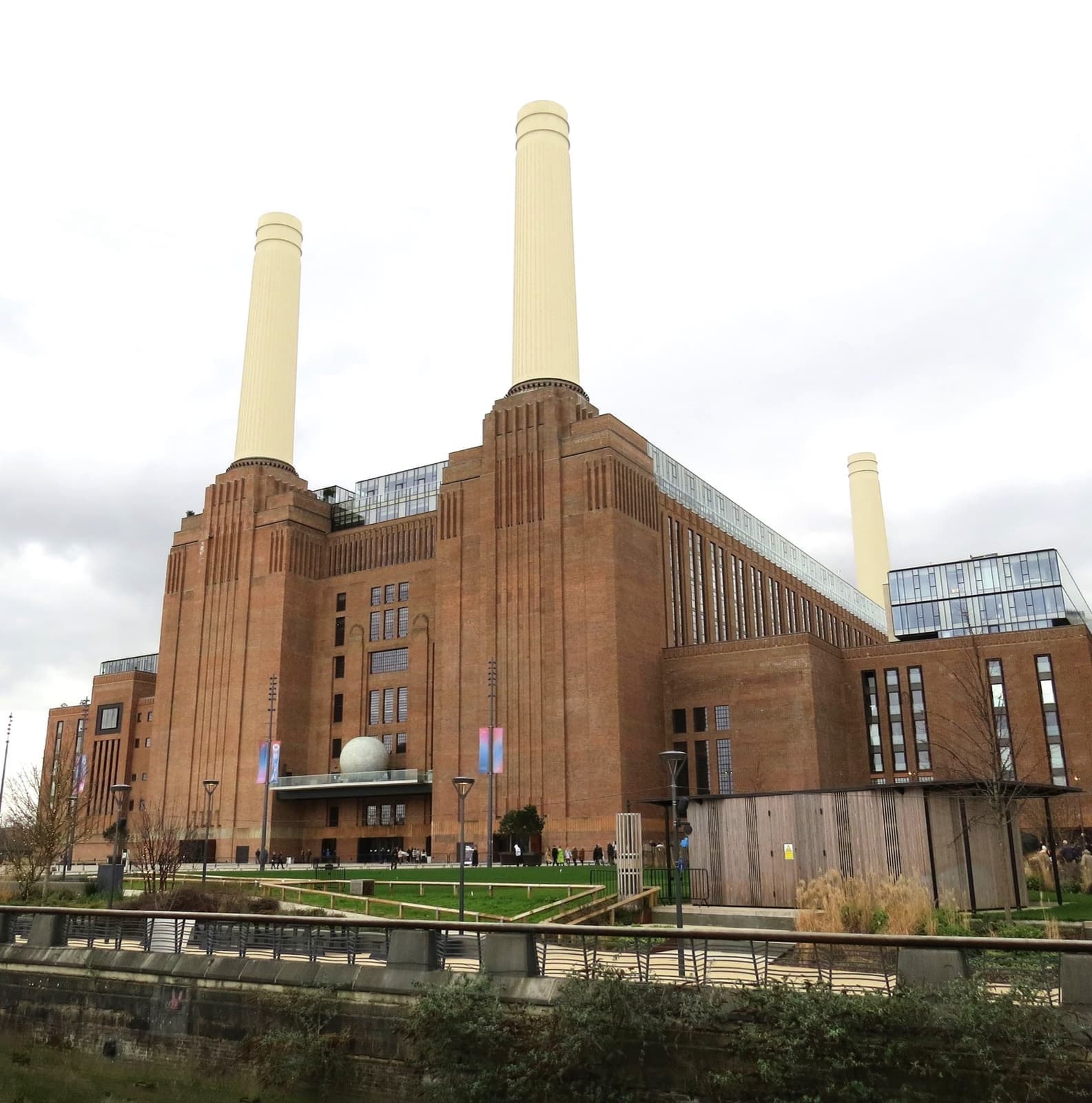 A brick power station with four white chimneys under a pale sky