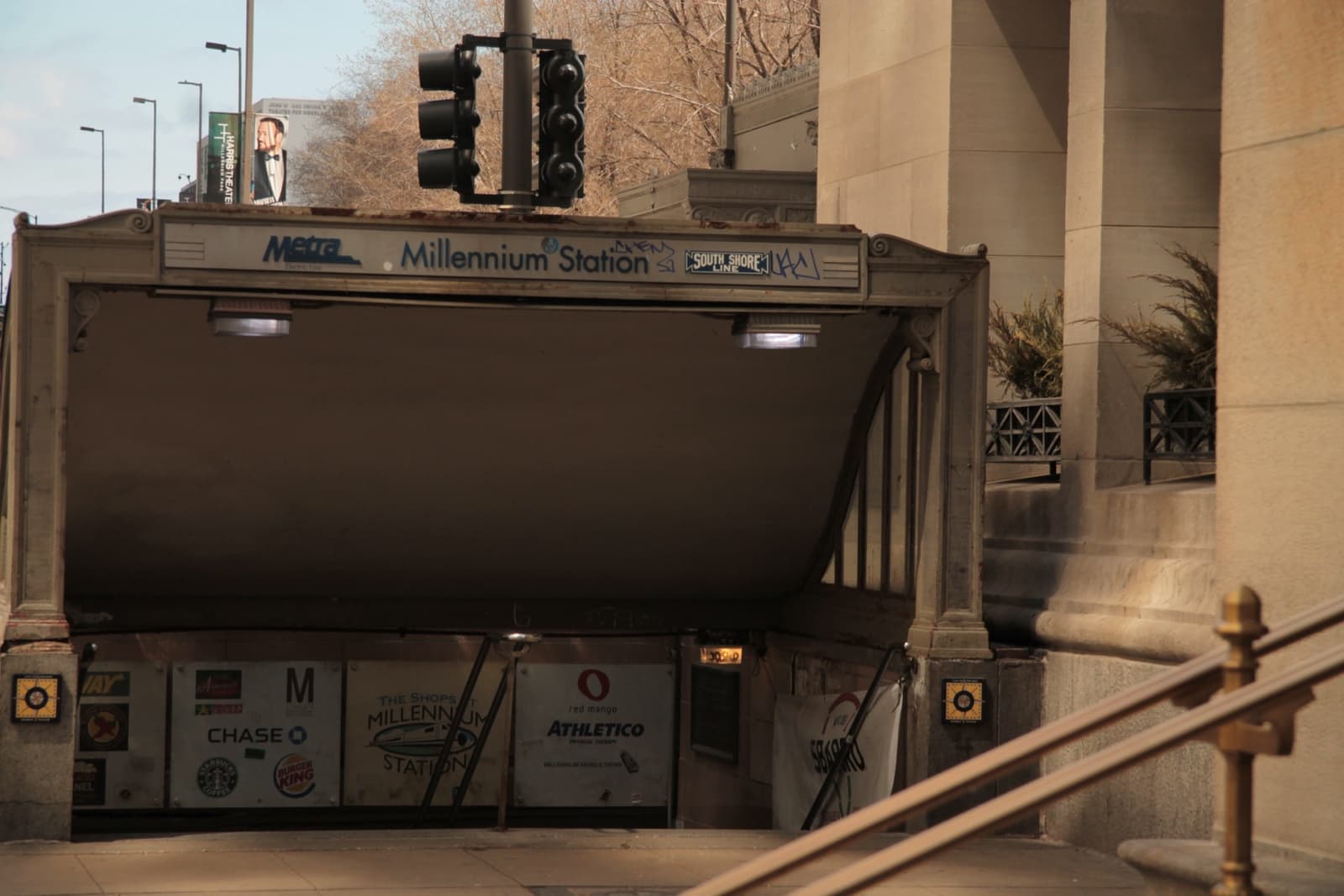 A stone stair entrance going down to Millennium Station under a street corner