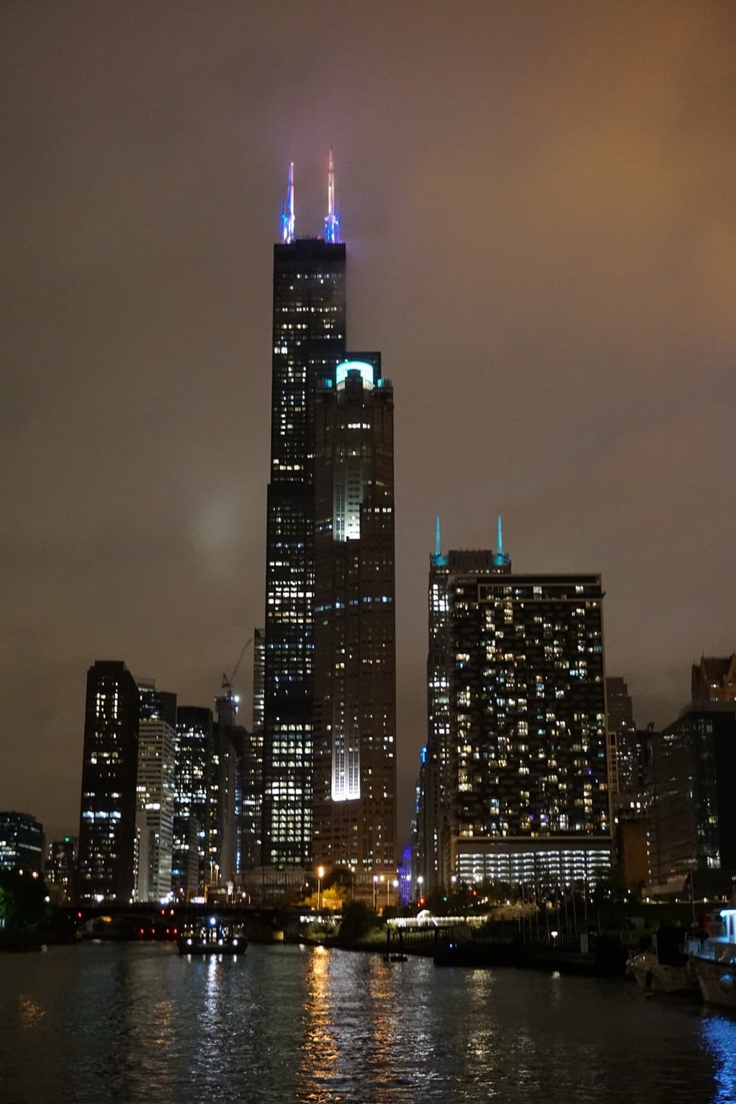 The black tower with two lit antennas above the Chicago River at night