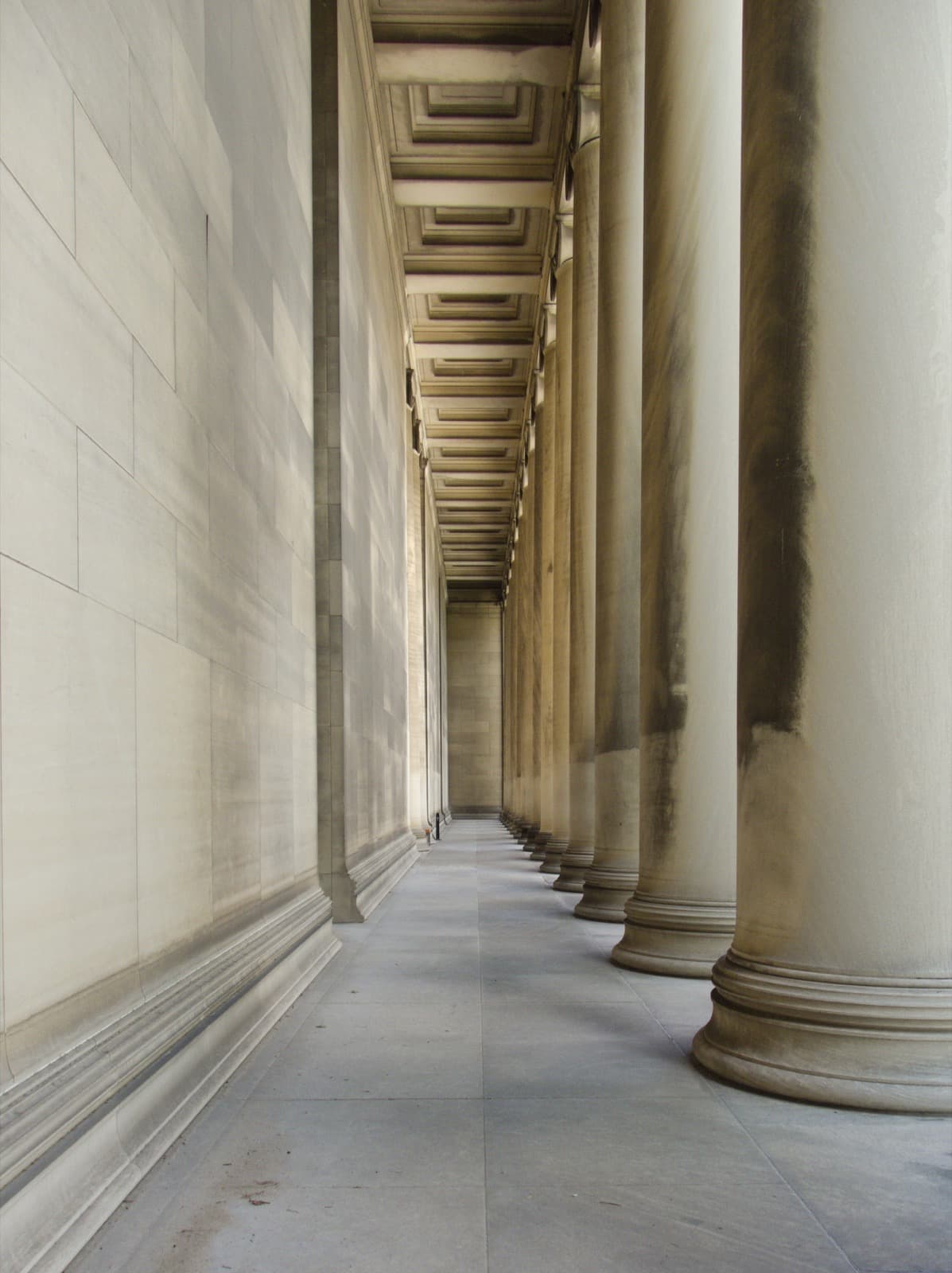 Tall stone columns seen from behind along a porch