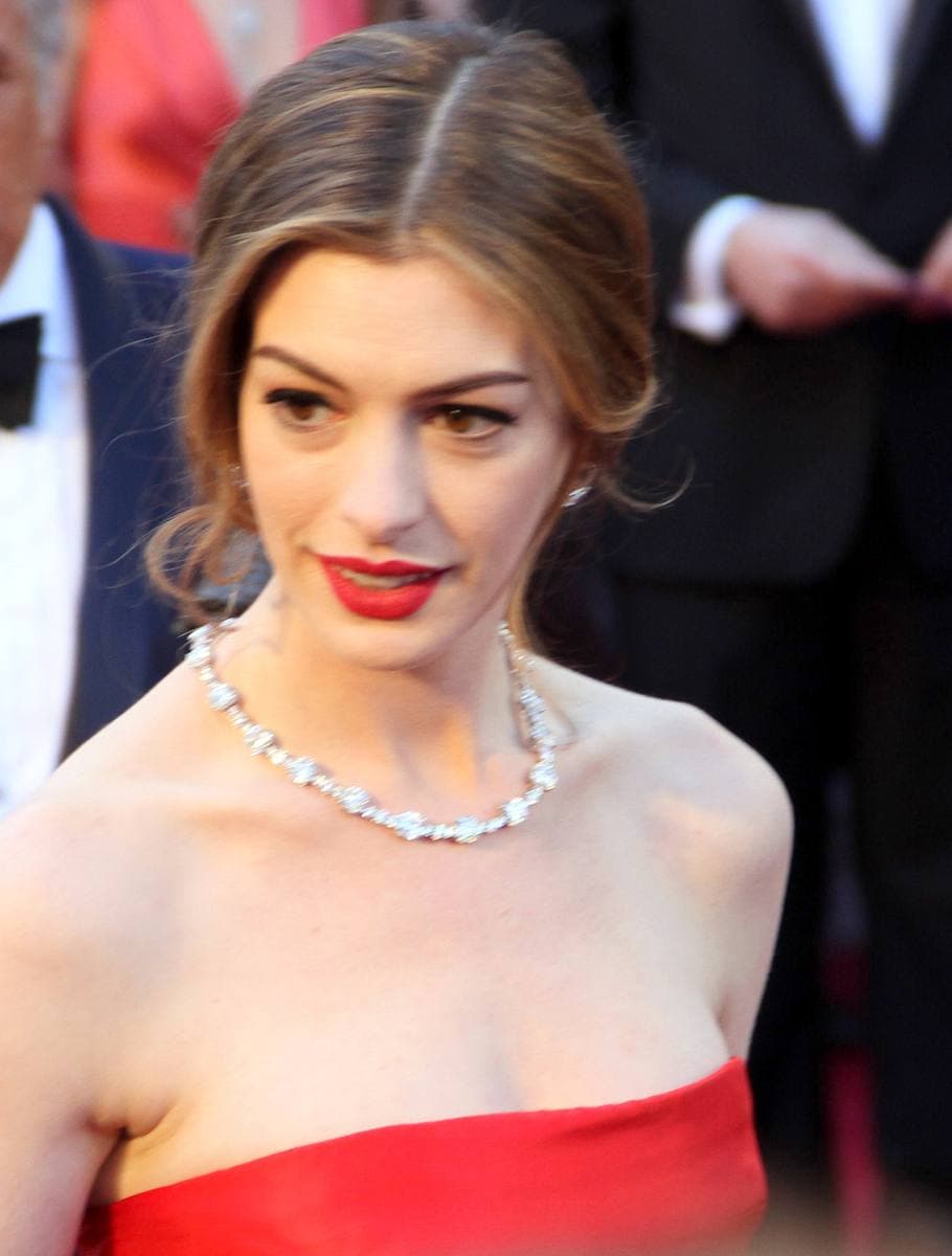 Anne Hathaway with her hair up in a red strapless dress and a diamond necklace