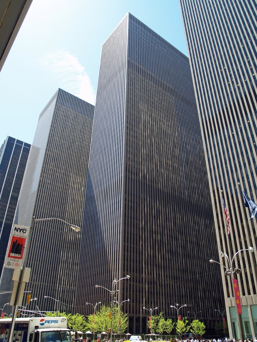 A grey tower with a band of dark windows seen from the street