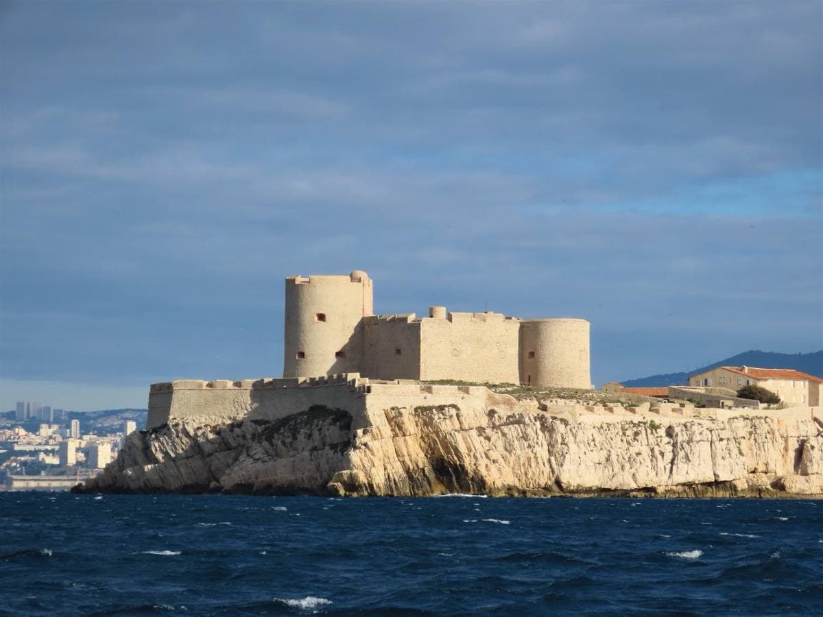 A pale stone fortress on a rocky island in blue water