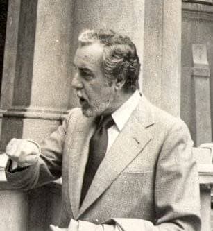 Black-and-white photograph of Fernando Rey with a grey beard, in a light suit, gesturing