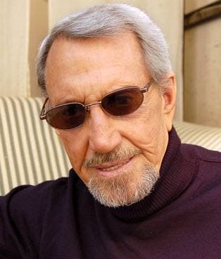 Colour photograph of Roy Scheider in tinted glasses and a dark jumper