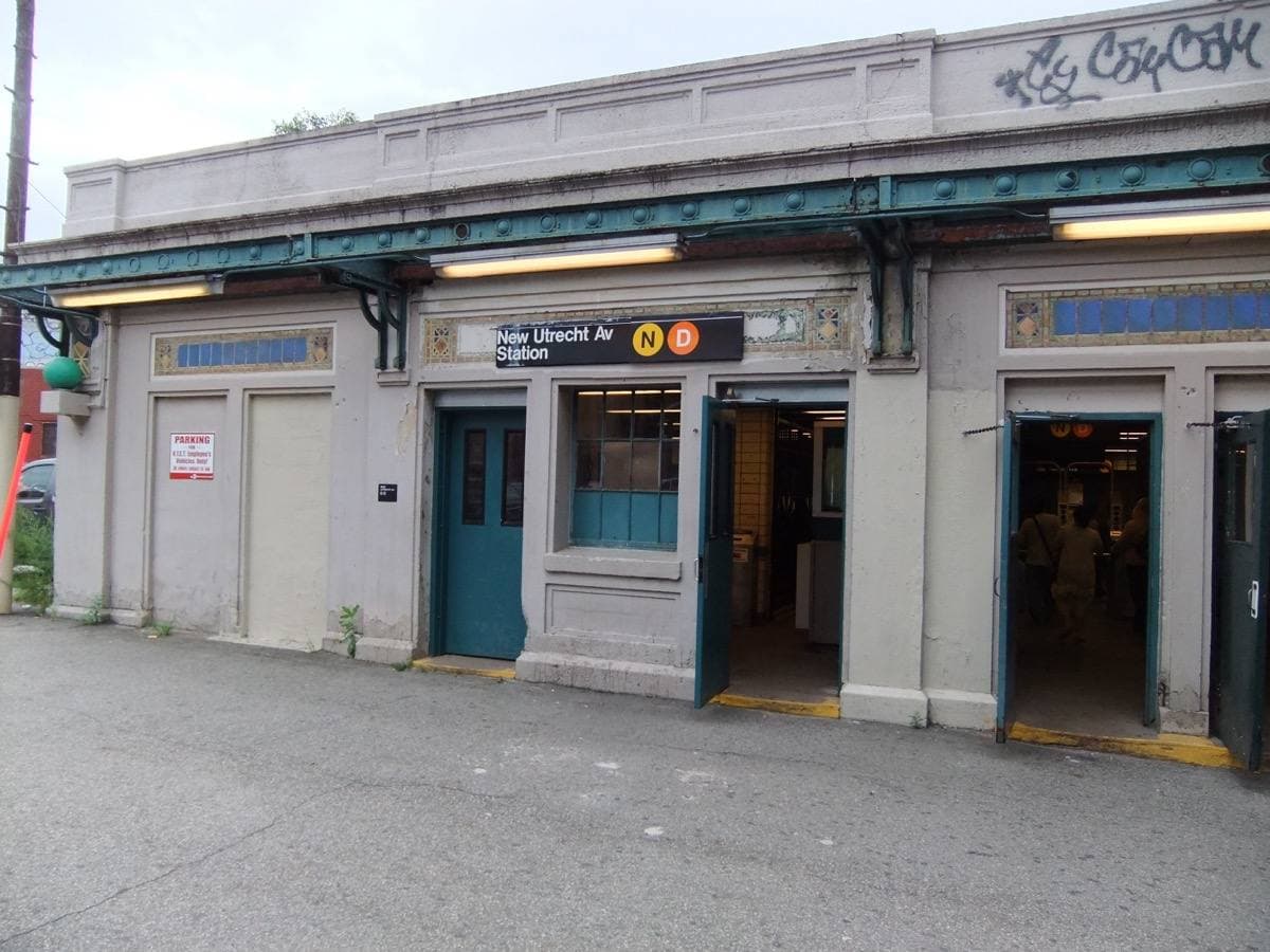 Low station building with arched doors beneath the elevated line