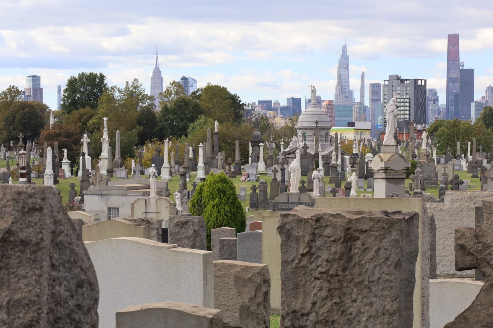Rows of headstones with the Manhattan skyline beyond