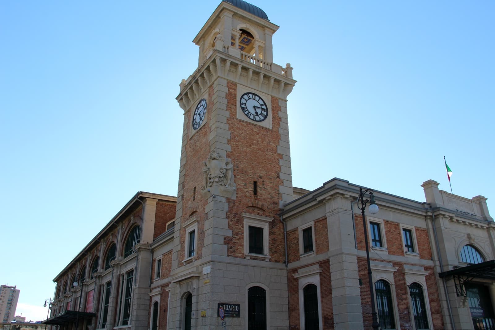 A brick and stone hall with a tall clock tower against a blue sky