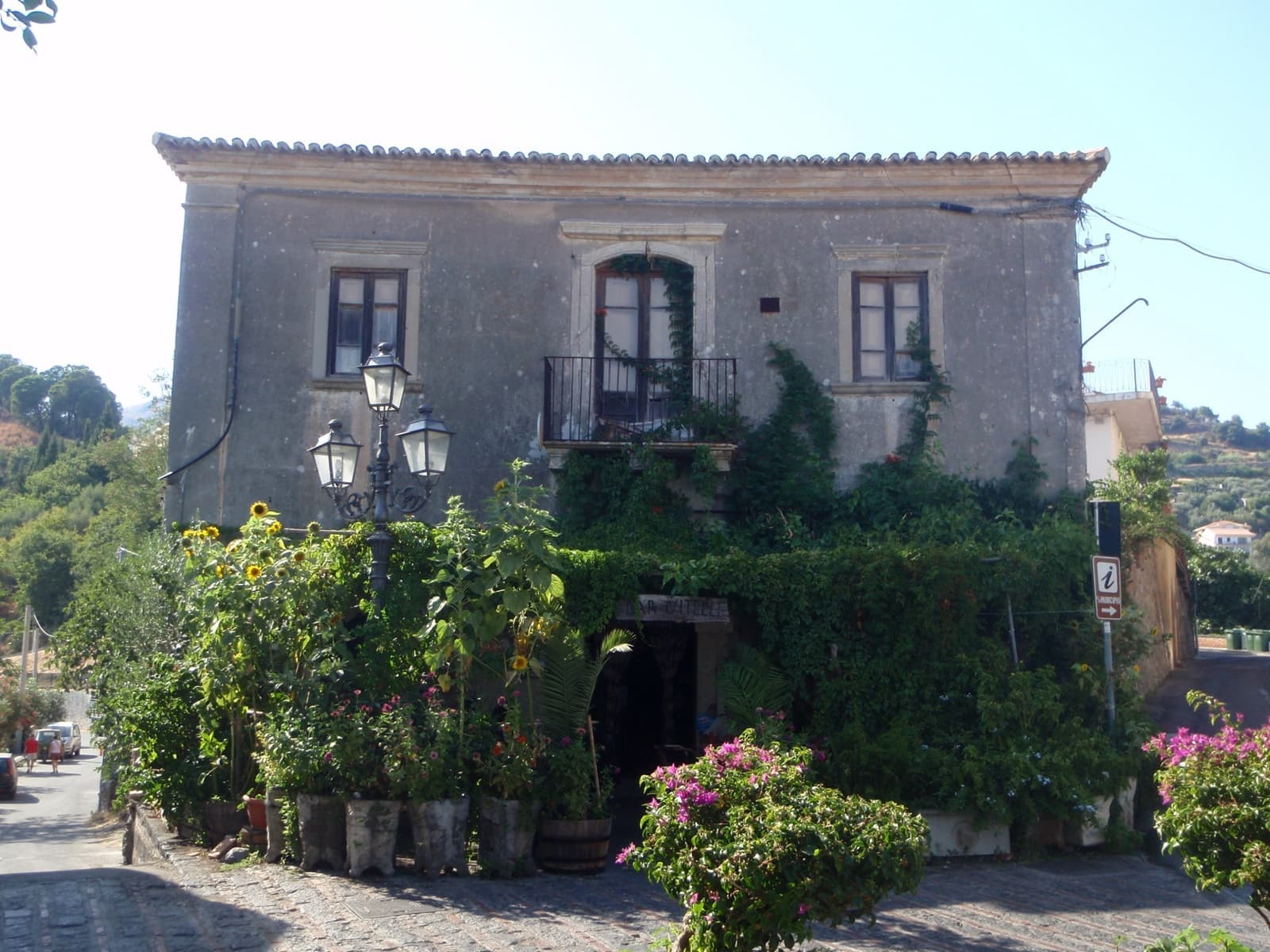 The stone front of Bar Vitelli with tables outside under a vine