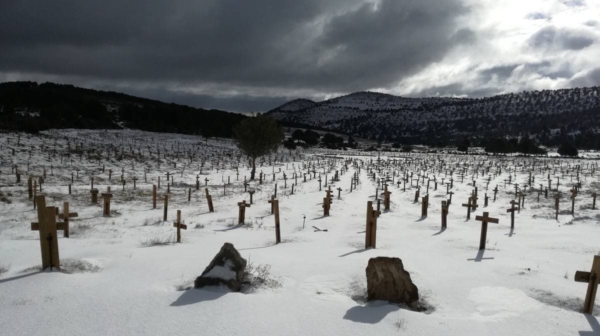 Rows of wooden crosses in snow under a dark sky