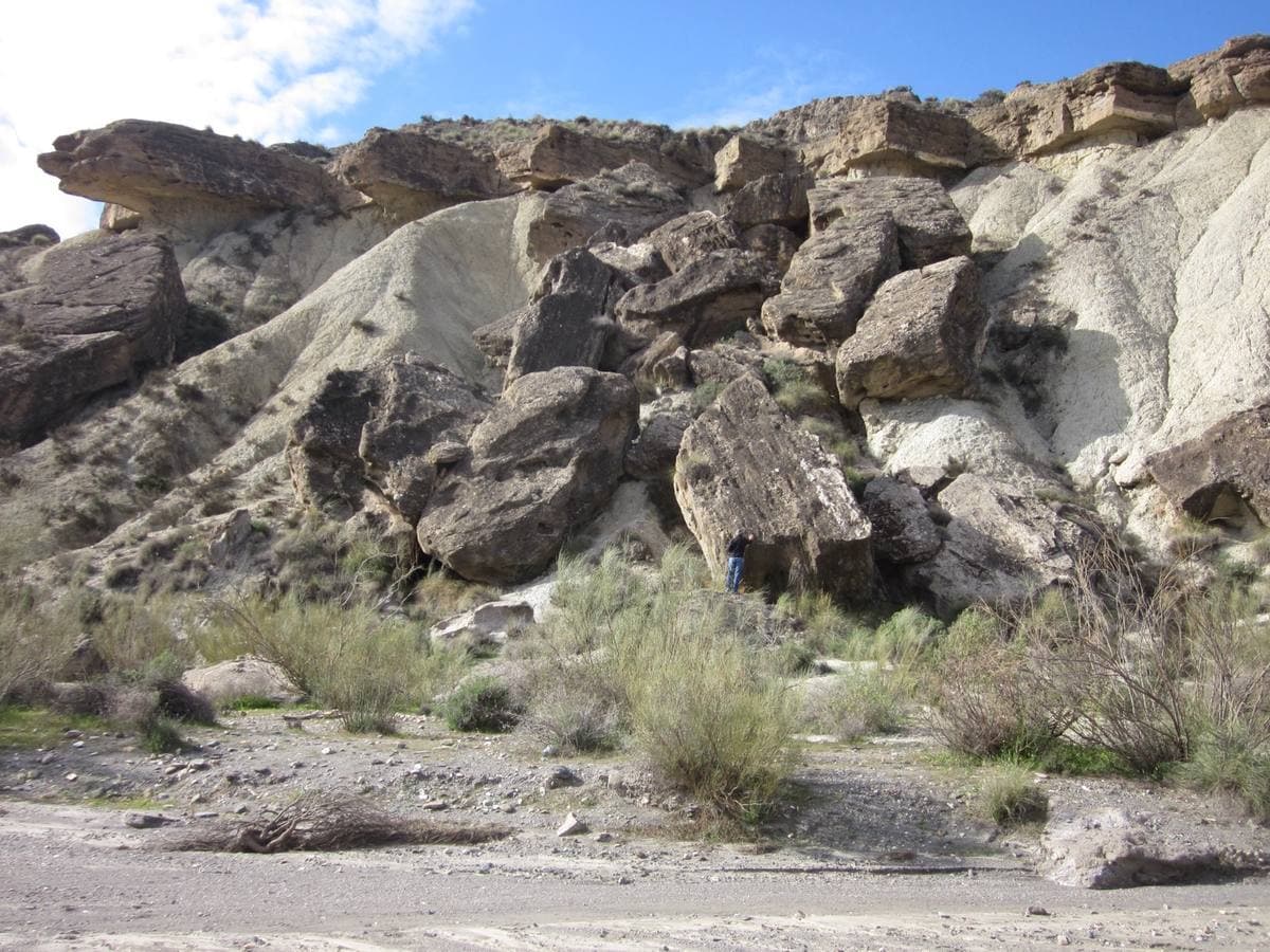 Pale eroded rock and scrub under a blue sky