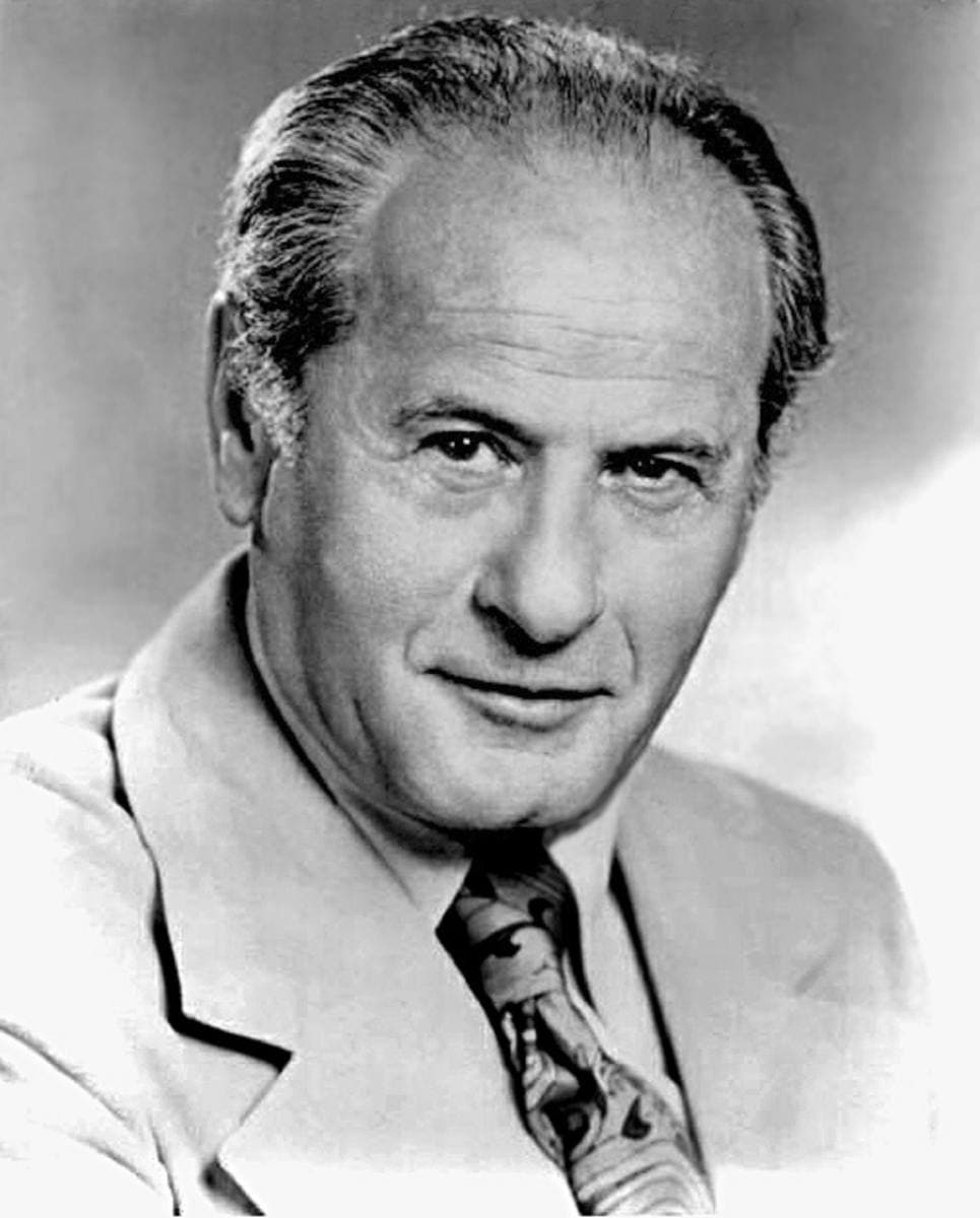 Eli Wallach smiling in a light suit and patterned tie, black and white