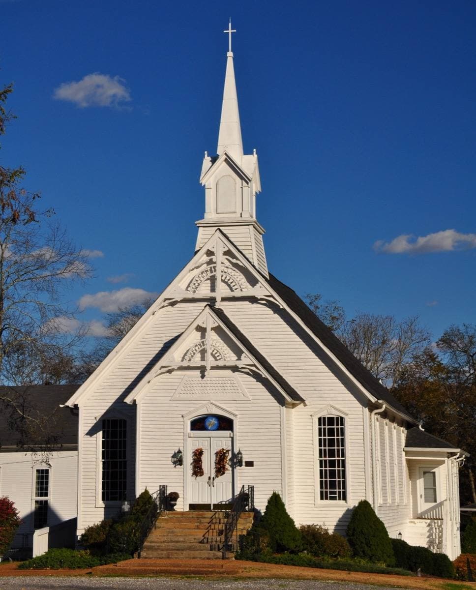 A small white wooden church with a pointed steeple in College Grove