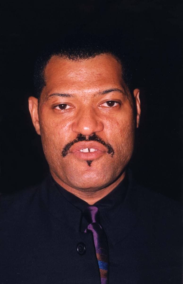 Laurence Fishburne with a moustache in a dark shirt and purple tie