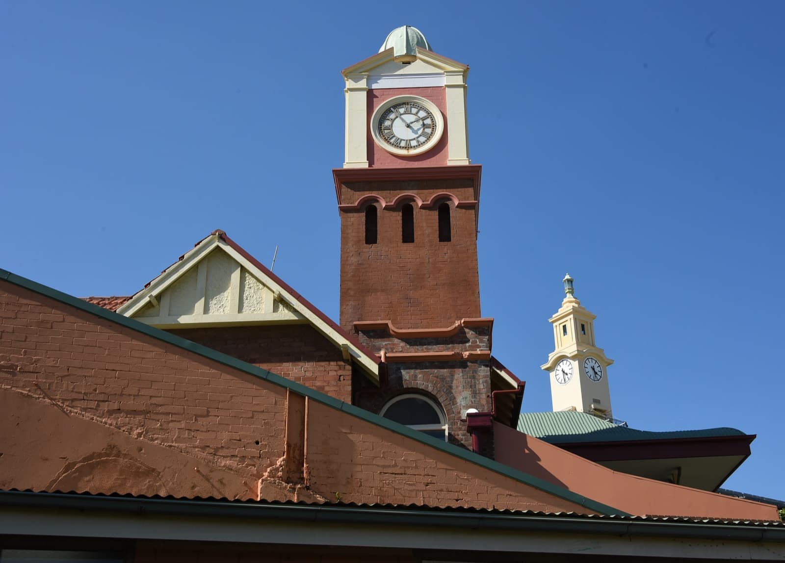 A red-brick clock tower with a white cupola above a terracotta roof