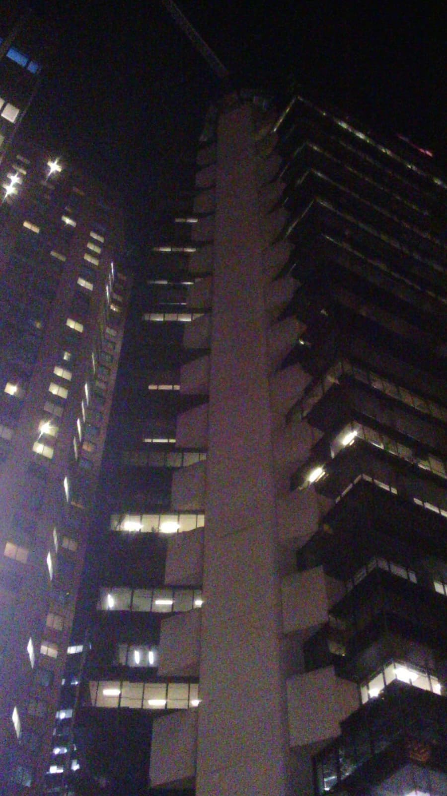 The dark tower at dusk, lit windows scattered up its face