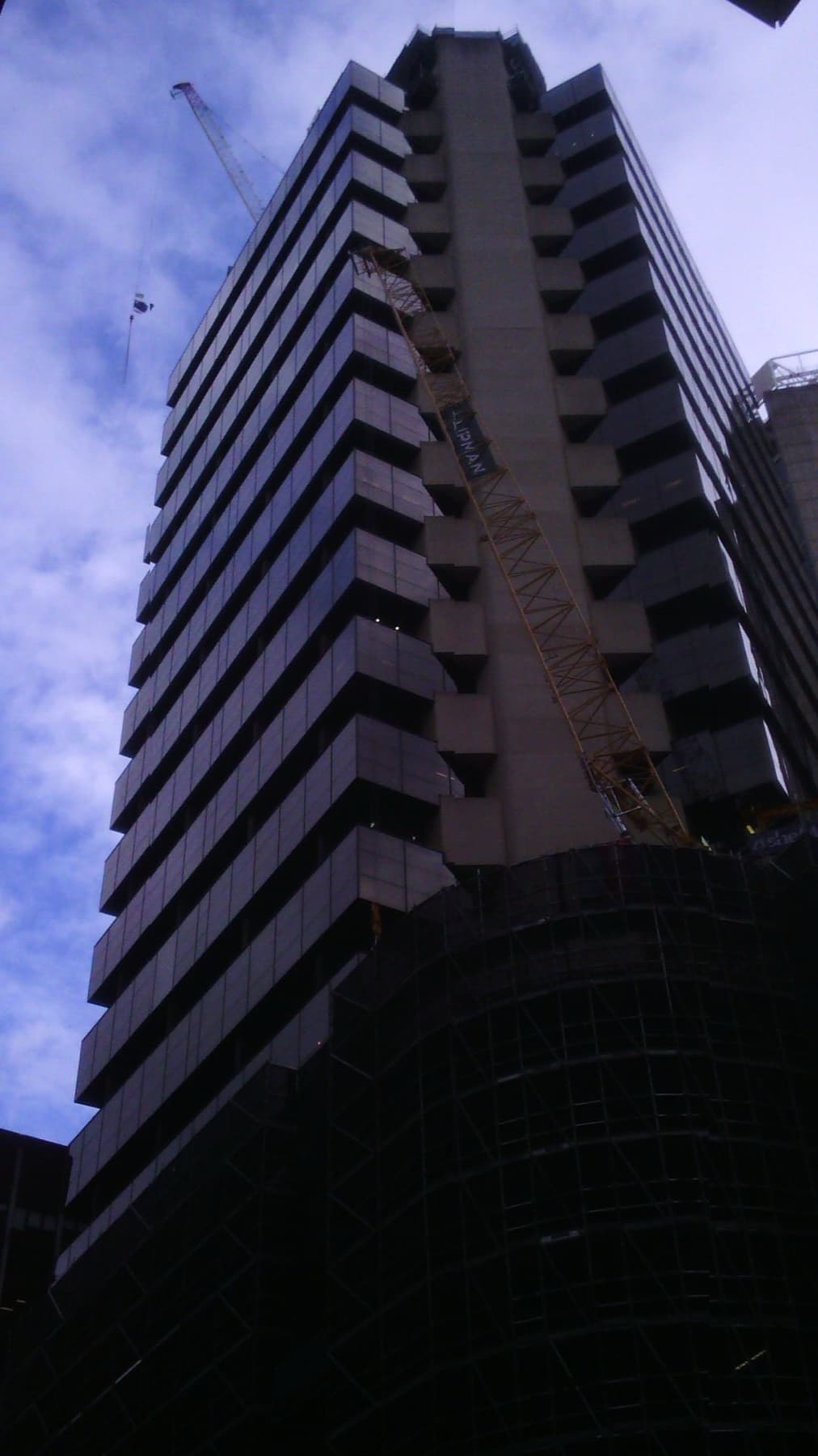 A dark office tower with stepped balconies against a blue sky