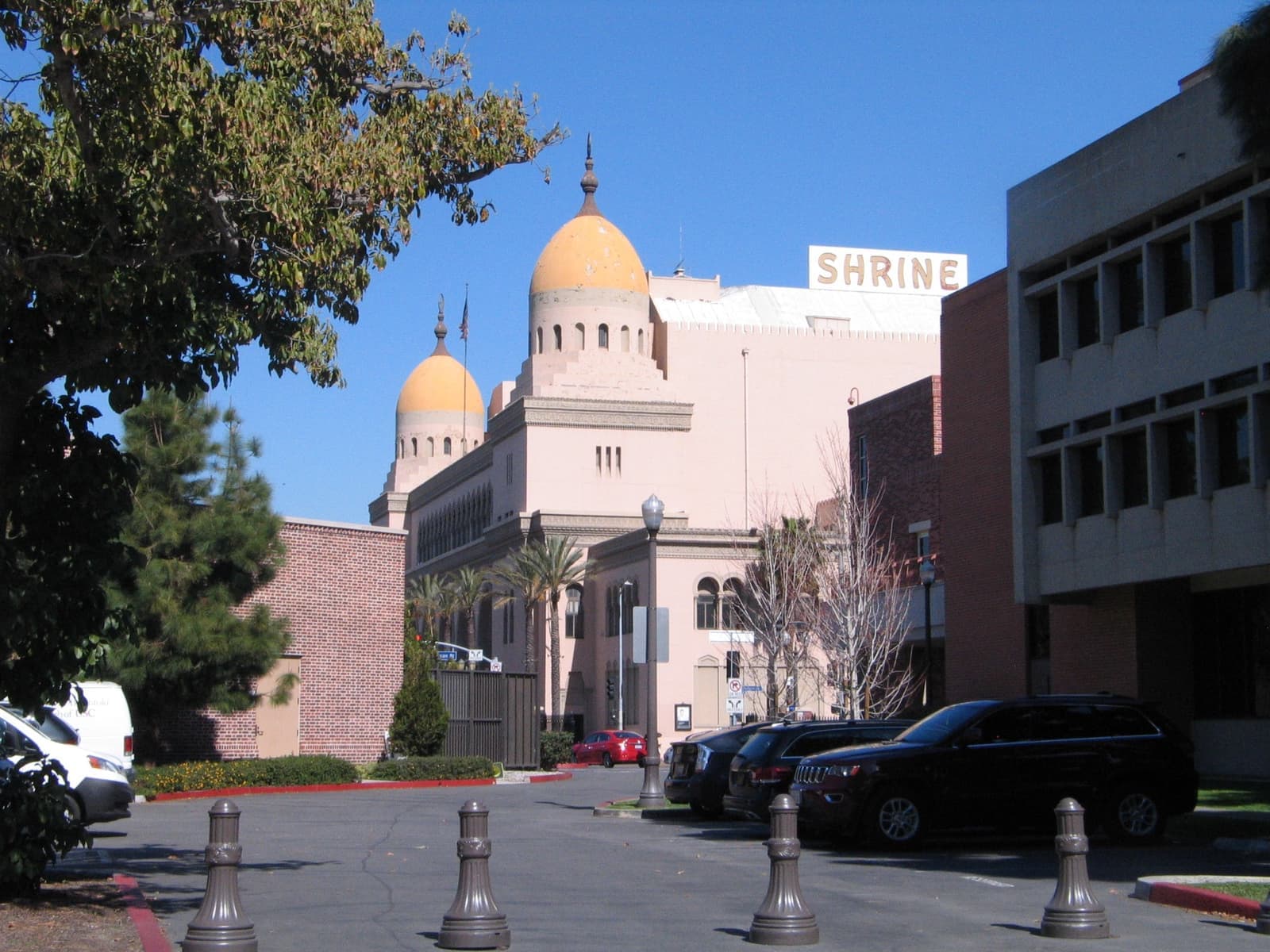 A pale Moorish-style building with two domes over a car park