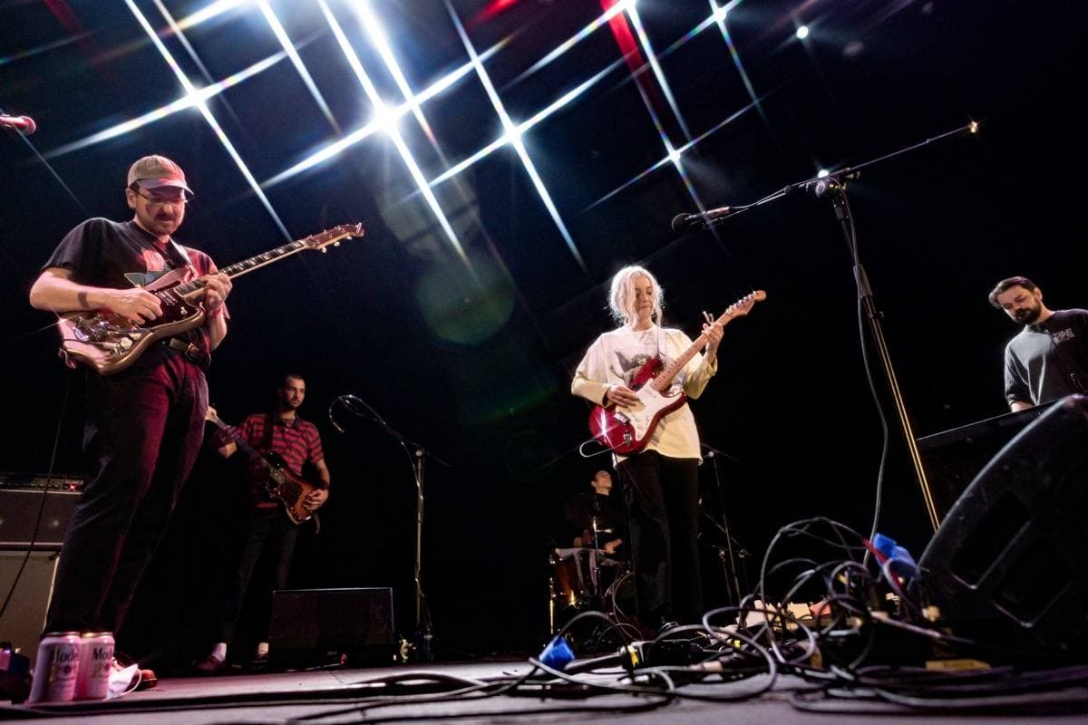 A band on a lit stage with light beams overhead
