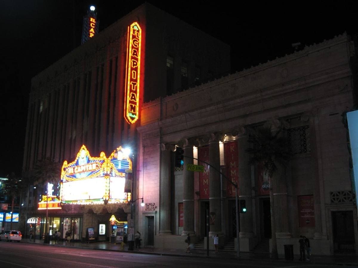 A theatre front with a lit marquee and a tall vertical sign at night