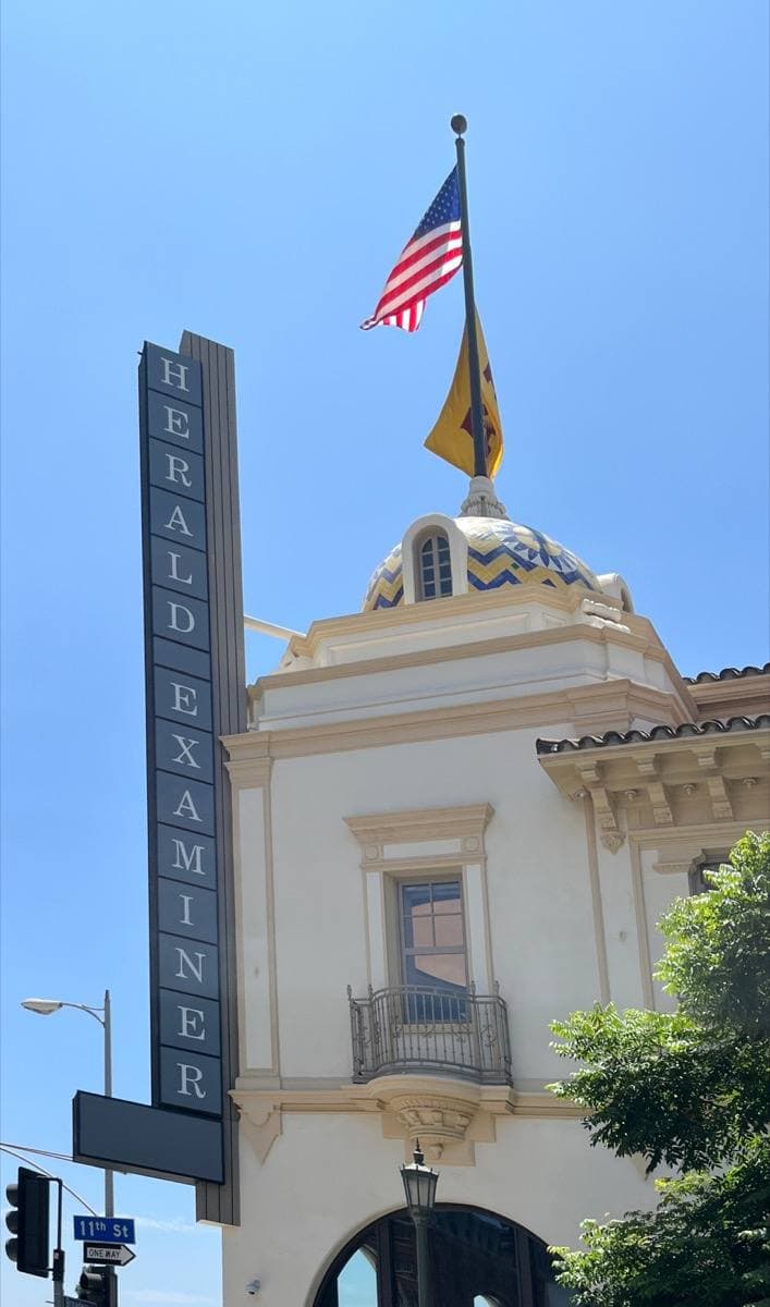 A white Mission-style tower with a vertical Herald Examiner sign