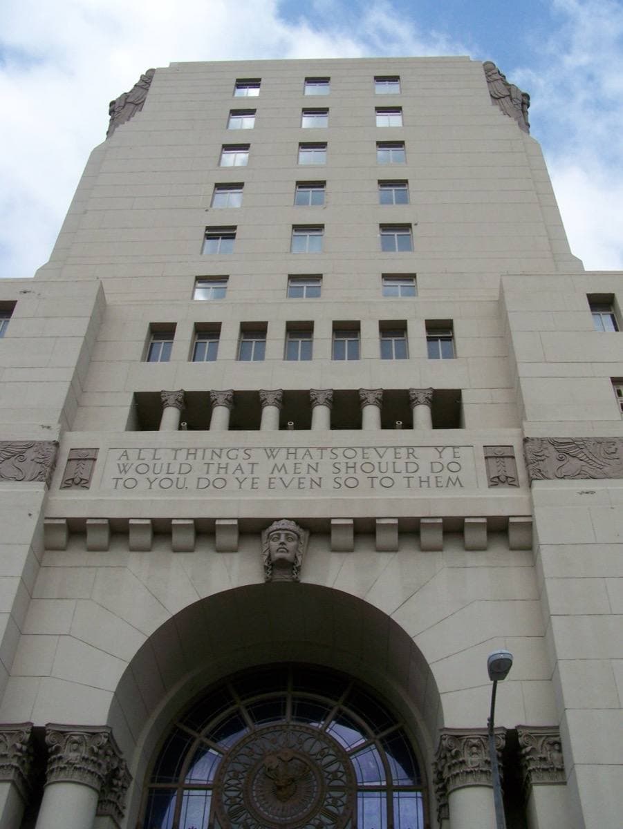 A tall stone building with an arched doorway, seen from below