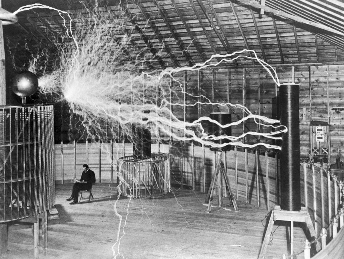 A man sits reading in a vast timber hall while long sparks branch across it
