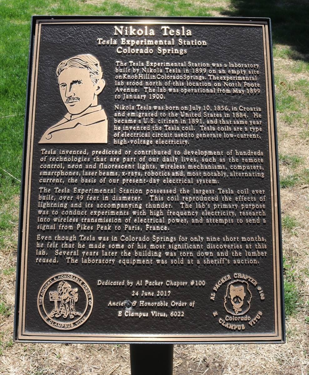 A bronze plaque on a post with Tesla’s portrait and text