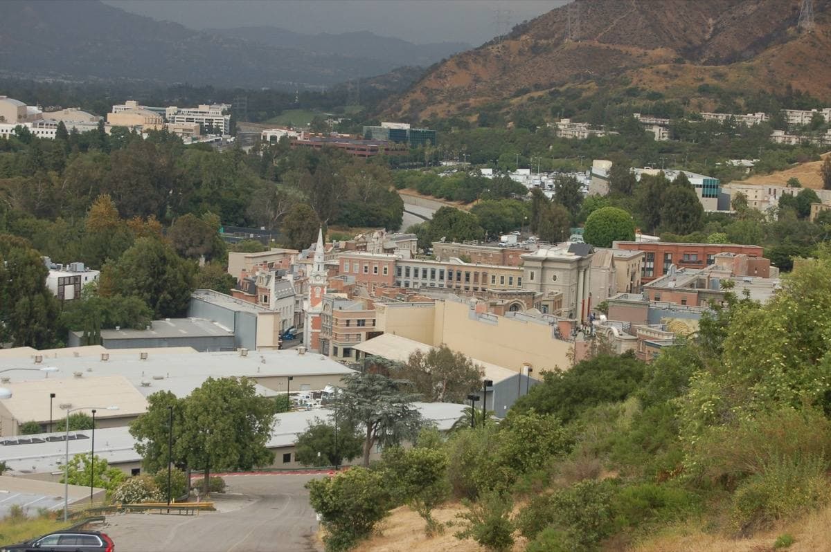 Rooftops of studio sets in a green valley with hills behind