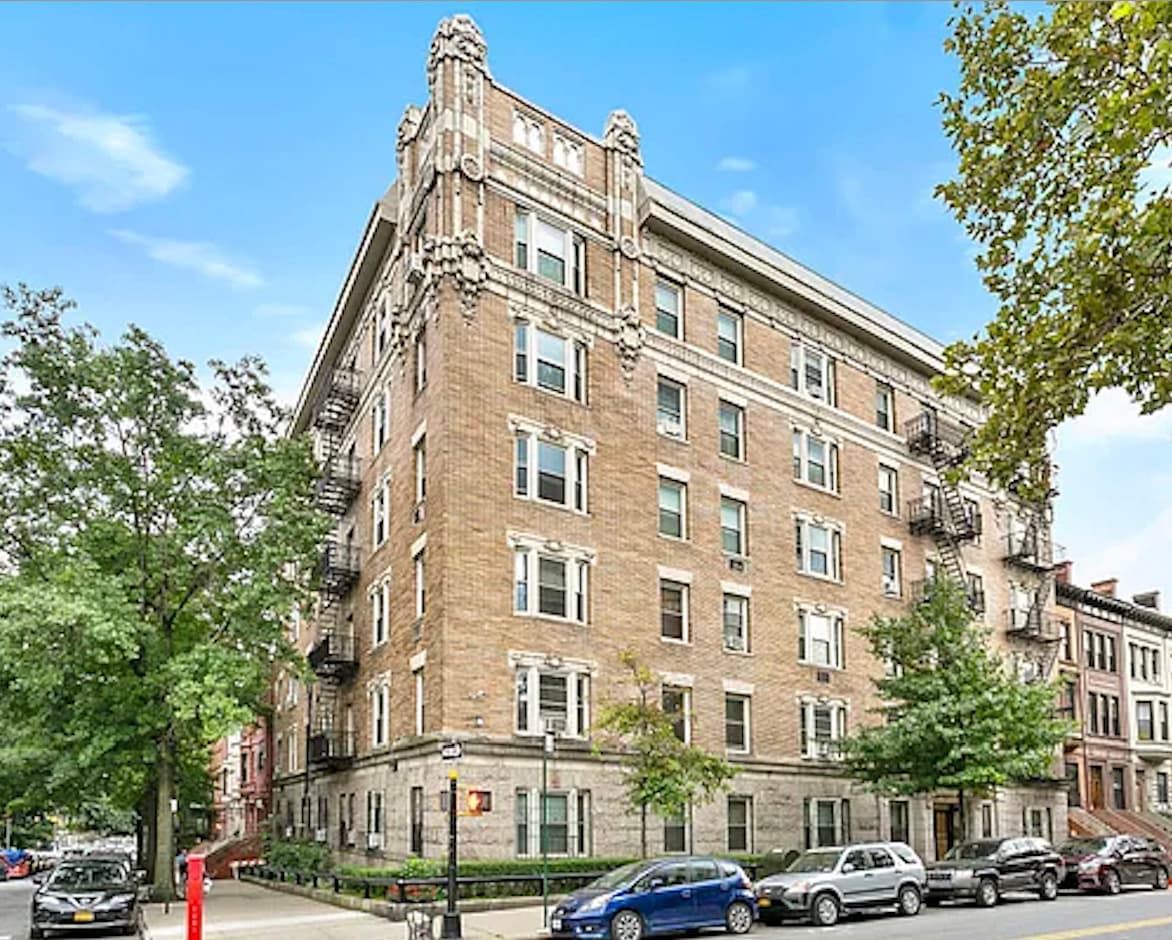 A tall apartment block on a Harlem street corner