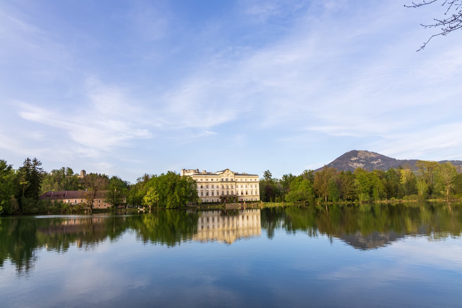 A pale palace on the far shore of a still lake, a mountain behind it