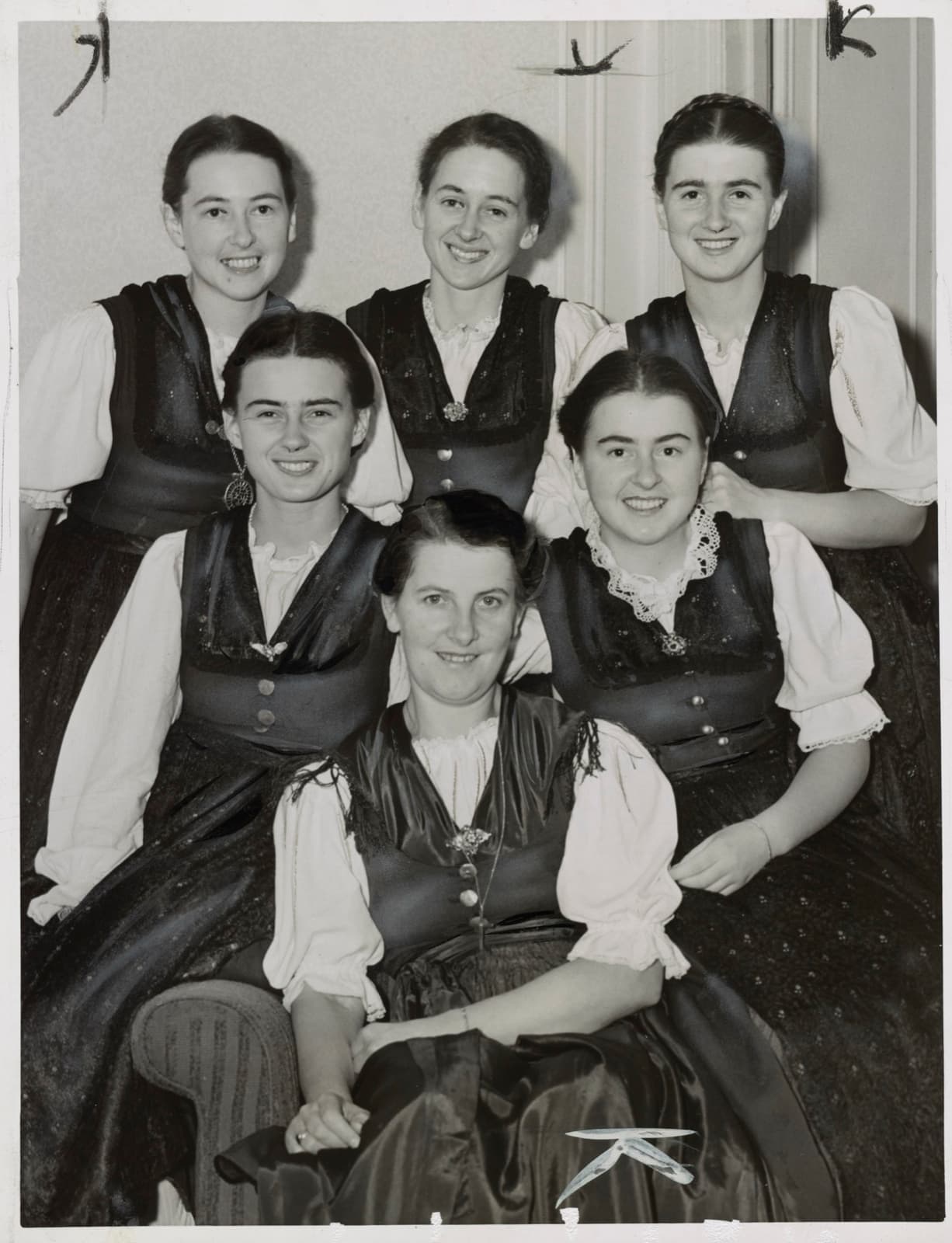 Six women in dirndls posed together, the eldest in front
