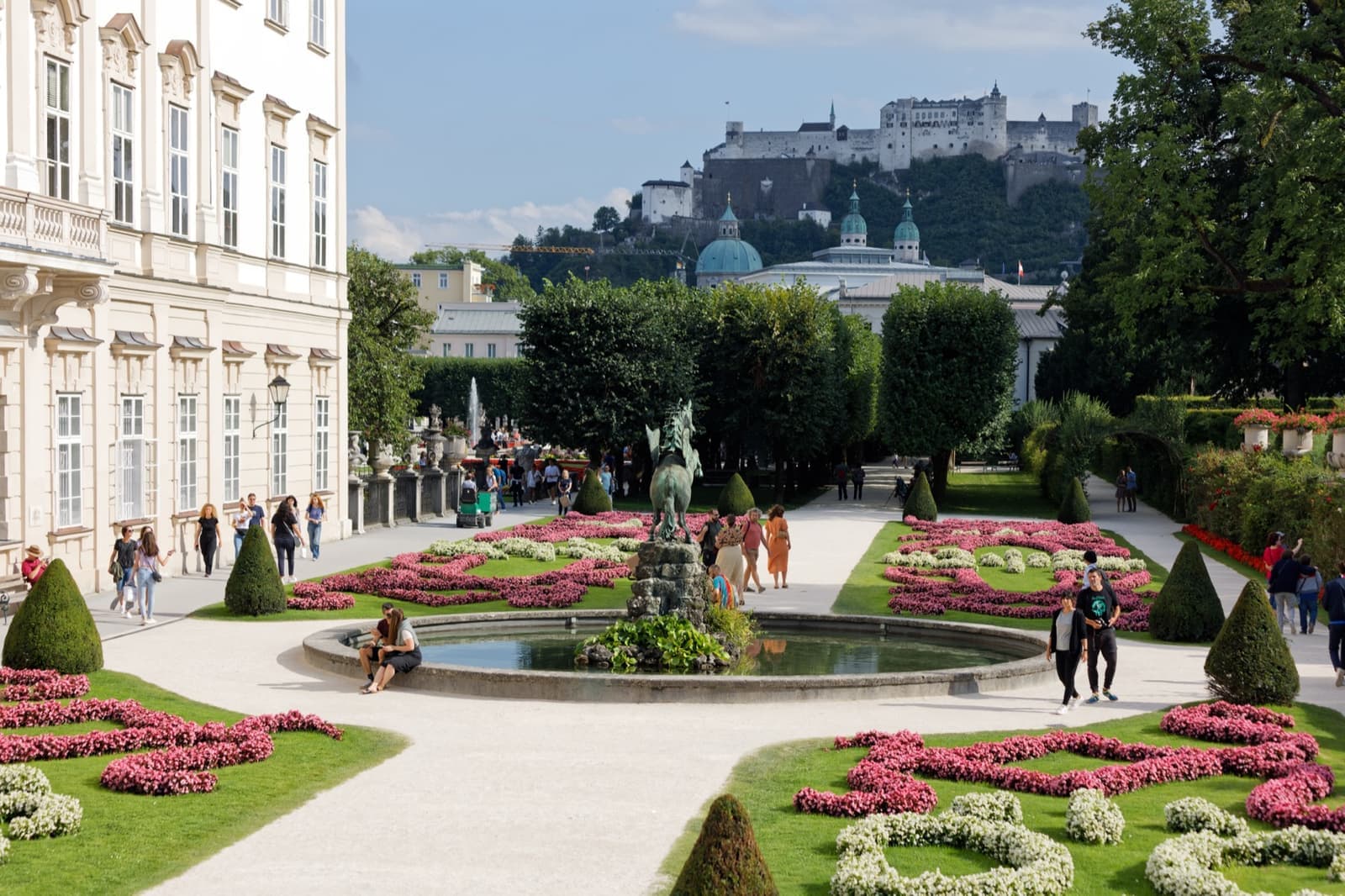 Flower beds and a fountain in a formal garden, a fortress on the hill beyond